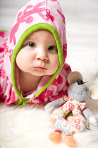 Baby in pink grüner Kapuze schaut in die Kamera